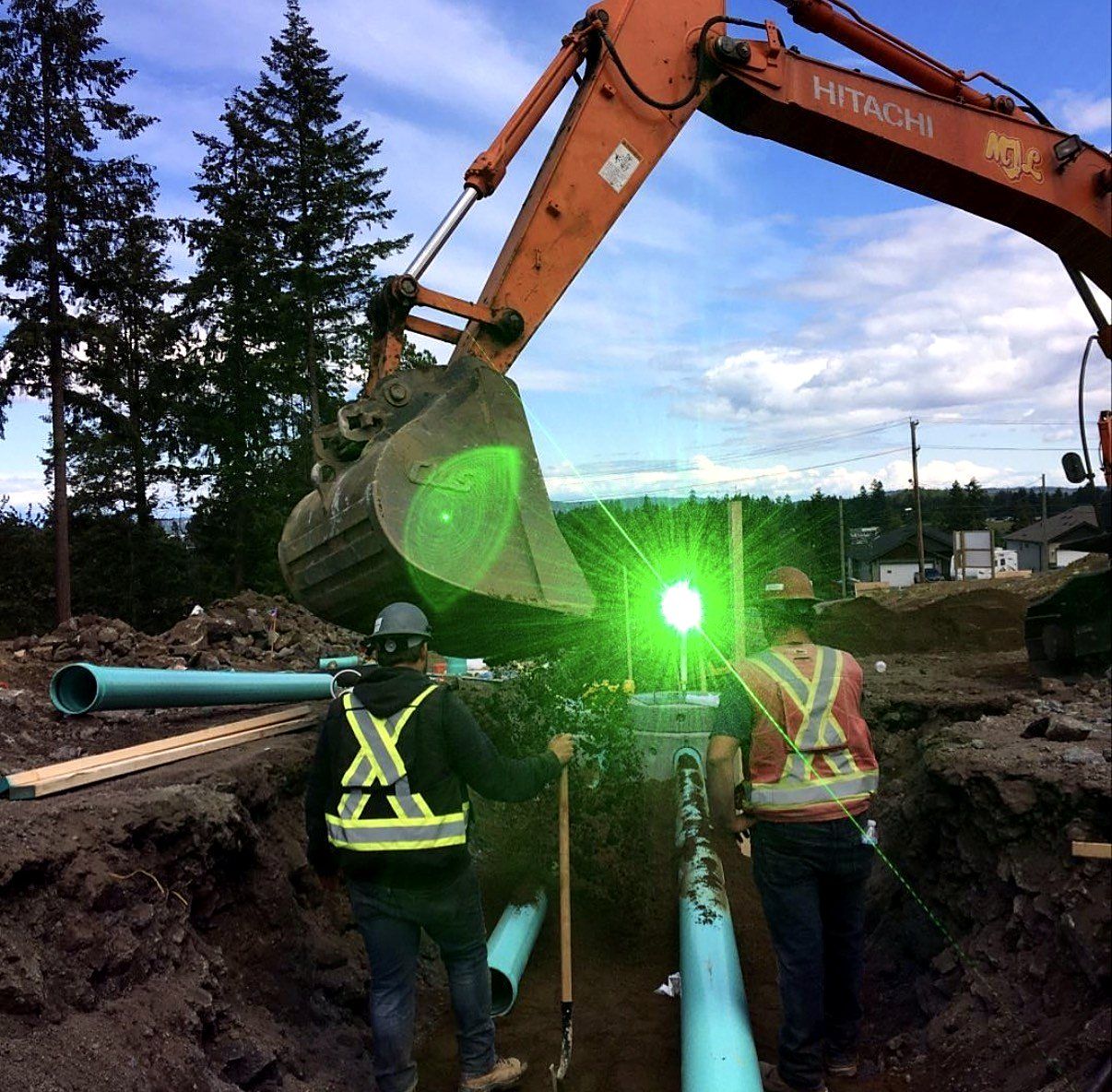 Crew laying sewer pipe to grade with a pipe laser