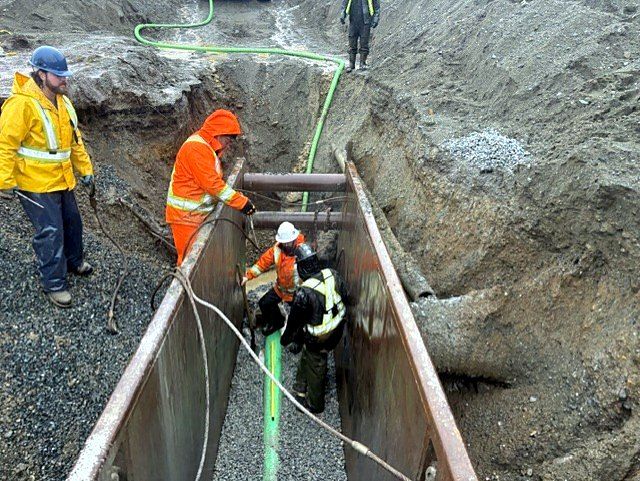 Crew working inside a trench box installing pipe