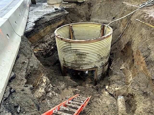 CSP manhole set beside a highway barrier