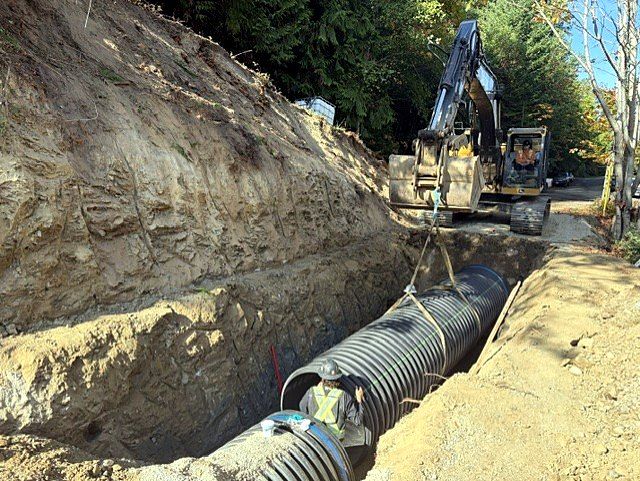 Large culvert being lowered into a deep trench