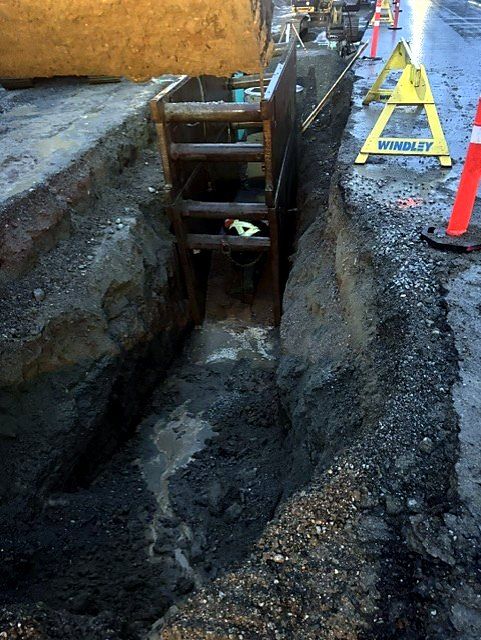 Shored trench in a city street with traffic control