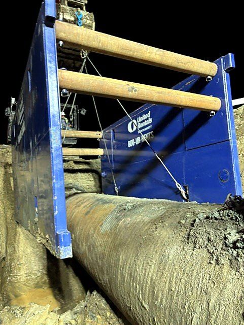 Trench box over a large-diameter pipe during a night shift